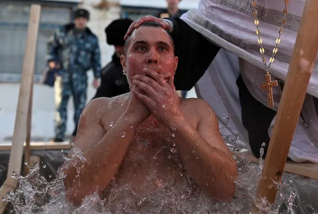 A priest conducts a ceremony as an inmate takes a dip in the freezing waters during celebrations of the upcoming Orthodox Christian feast of Epiphany at a high-security penal colony in Omsk, Russia on January 18, 2020. (Photo by Alexey Malgavko/Reuters)