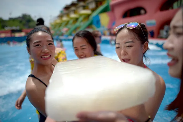 Visitors hold ice blocks to cool themselves in hot weather at a water park on June 23, 2016 in Chongqing, China. Citizens and visitors escaped high temperature at a water park in Yangren Jie (also known as Foreigner Street), Nan'an District of south China's Chongqing. (Photo by VCG/VCG via Getty Images)