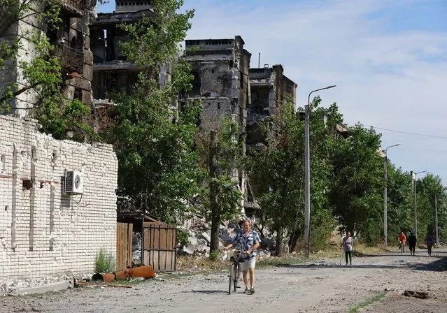 Local residents walk past apartment buildings destroyed during Ukraine-Russia conflict in the city of Sievierodonetsk in the Luhansk Region, Ukraine on June 30, 2022. (Photo by Alexander Ermochenko/Reuters)