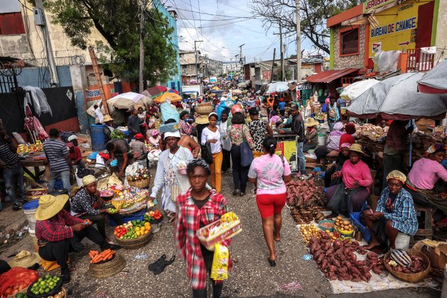 People walk through the Petionville street market in Port-au-Prince, Haiti, on May 2, 2024. Nearly half of the country’s population is struggling to feed themselves due to the conflict, unable to work, the families depend on food rations and hygiene kits brought in by non-governmental organizations. “We can't do anything - there's no money, no trade”, said Mirriam Auge, 45, a mother who was forced out of her home three months ago. “We lost everything in our homes, I cried while everyone was sleeping”. (Photo by Ricardo Arduengo/Reuters)