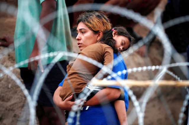 A migrant girl sleeps in her mother's arms after walking through the Rio Grande river in an attempt to seek asylum into the U. S., as seen from Piedras Negras, Mexico on September 30, 2023. (Photo by Daniel Becerri/Reuters)