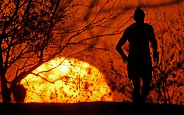 A man runs in a park as the sun sets, Wednesday, April 8, 2020, in Kansas City, Mo. The city is under a stay-at-home order, asking everyone to stay inside and away from others as much as possible, in an effort to slow the spread of the new coronavirus. (Photo by Charlie Riedel/AP Photo)