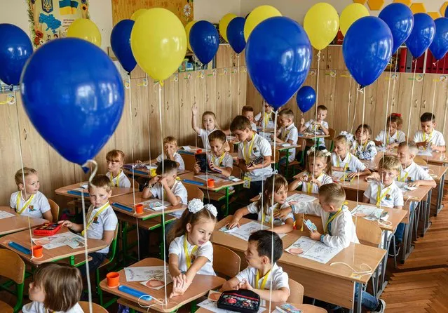 Pupils of the first grade attend the first lesson of the new school year in the western Ukrainian city of Lviv on September 1, 2022. Ukrainian authorities said 2,199 educational institutions had been damaged as a result of bombing and shelling, with 225 of them completely destroyed. Half of the 23,000 schools surveyed by the education ministry – about 51 percent – are equipped with the bunker facilities necessary to begin classes offline. (Photo by Yuriy Dyachyshyn/AFP Photo)