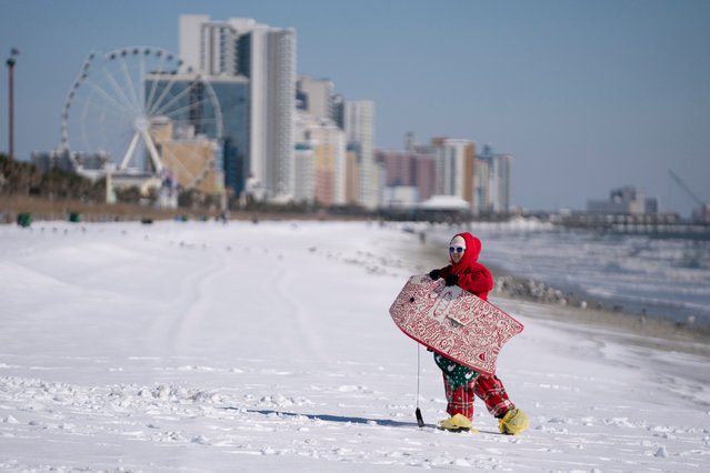 Savannah Wingard walks up the beach while using a boogie board as a sled on January 22, 2025 in Myrtle Beach, South Carolina. A winter storm brought heavy bands of snow and sleet to much of the Southern U.S., causing hazardous travel conditions to areas that rarely see snow. (Photo by Sean Rayford/Getty Images)