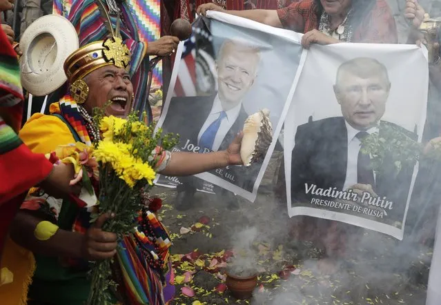 Shamans hold photos of U.S. President Joe Biden and Russia's President Vladimir Putin during a year-end ritual where they predict political and social issues expected to occur in next year in Lima, Peru, Wednesday, December 29, 2021. The shamans made symbolic payment to Mother Earth while asking that the COVID-19 pandemic come to an end and that world leaders be cleansed so they can make wise decisions in the coming year. (Photo by Guadalupe Pardo/AP Photo)