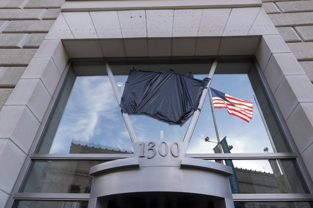The American flag flying alone beside an empty flagpole that previously had the flag of the U.S. Agency for International Development, or USAID, are pictured in the reflection of a window that previously had the sign and the seal of USAID, outside the agency's headquarters in Washington, Friday, February 7, 2025. (Photo by Jose Luis Magana/AP Photo)