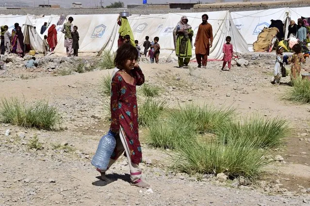 A flood victim walks to get drinking water at a relief camp in Dasht near Quetta, Pakistan, Friday, September 16, 2022. (Photo by Arshad Butt/AP Photo)