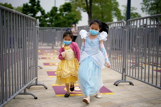 Children wearing face masks walk past social distancing markers to enter the Shanghai Disneyland theme park which reopens following a shutdown due to the coronavirus disease (COVID-19) outbreak, at Shanghai Disney Resort in Shanghai, China on May 11, 2020. (Photo by Aly Song/Reuters)