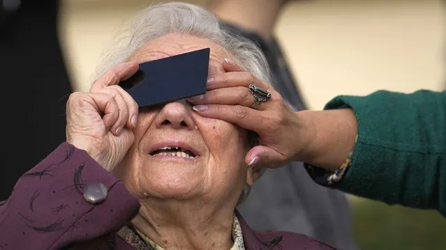 An elderly woman looks through a welding filter during a partial solar eclipse in Bucharest, Romania, Tuesday, October 25, 2022. (Photo by Vadim Ghirda/AP Photo)