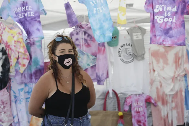 Taylor Medina wears a mask as she sells her fashions Saturday, June 27, 2020, in Huntington Beach, Calif. (Photo by Marcio Jose Sanchez/AP Photo)