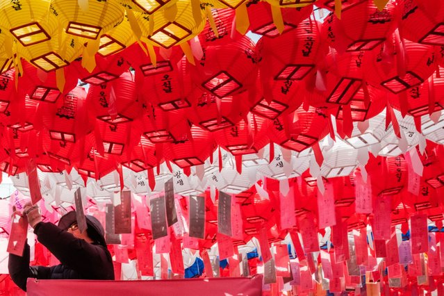 A man on a lift ties a wish card to one of the lanterns hanging above the grounds at the Jogyesa Temple in Seoul on March 21, 2025, ahead of the Lotus Lantern Festival in May, which celebrates Buddha's birthday. (Photo by Yasuyoshi Chiba/AFP Photo)