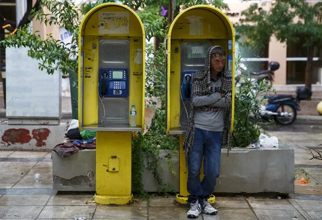 An Afghan refugee seeks shelter in a phone booth during a rain storm in Victoria Square, where hundreds of migrants and refugees sleep rough, in central Athens, Greece, September 21, 2015. Bitterly divided European heads of state will seek to find a credible response to the worst migration crisis affecting the continent since World War Two at Wednesday's emergency summit. (Photo by Paul Hanna/Reuters)