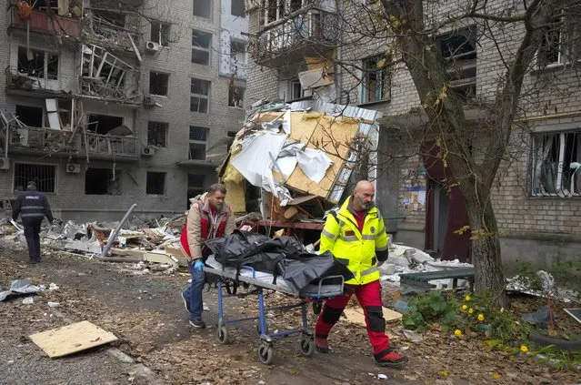 Medics carry the lifeless body of a victim found under rubble at the scene of night shelling in Mykolaiv, Ukraine, Friday, November 11, 2022. (Photo by Efrem Lukatsky/AP Photo)