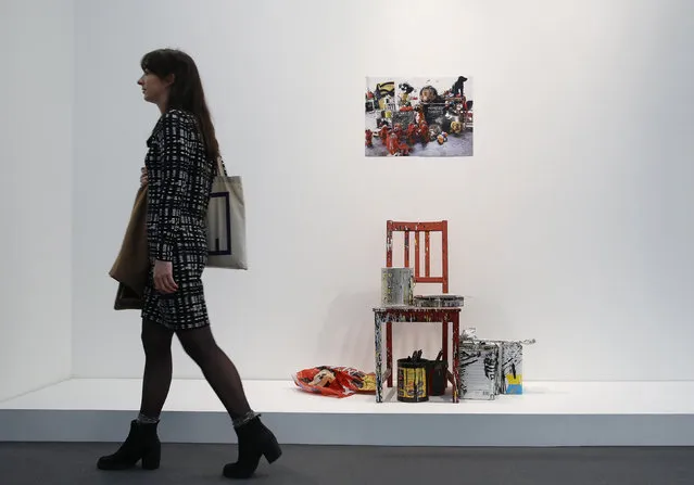 A visitor poses with artist Joyce Pensato's artwork “Red Chair (for Charlie)” at the Frieze Art Fair in London, October 14, 2014. (Photo by Luke MacGregor/Reuters)