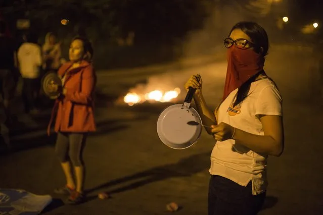 Anti-government demonstrators bang cooking pot in protest during a government imposed dawn-to-dusk curfew in Tegucigalpa, Honduras, late Sunday, December 3, 2017. Honduran electoral authorities have restarted the long-delayed count of ballots from last weekend's presidential election amid protests by supporters of opposition candidate Salvador Nasralla, who is calling for a re-do of the vote. (Photo by Rodrigo Abd/AP Photo)