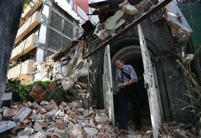 A man walks through a door in a building that collapsed during a 7.1 magnitude earthquake in the Condesa neighborhood of Mexico City, Tuesday, September 19, 2017. (Photo by Marco Ugarte/AP Photo)
