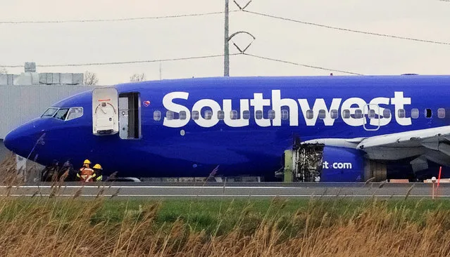 Emergency personnel monitor the damaged engine of Southwest Airlines Flight 1380, which diverted to the Philadelphia International Airport this morning after the airline crew reported damage to one of the aircraft's engines, on a runway in Philadelphia, Pennsylvania U.S. April 17, 2018. (Photo by Mark Makela/Reuters)