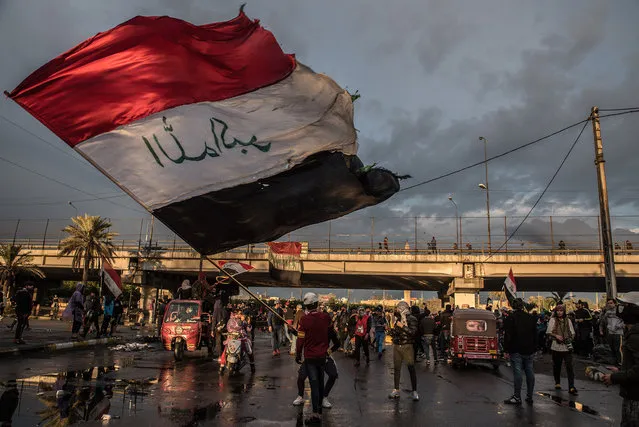 Iraq: One Hundred Days of Thawra. A man waving the Iraqi flag during a symbolic funeral march for a protester killed in clashes with security forces the previous day. Baghdad, 21 January 2020. (Photo by Emilienne Malfatto for The Washington Post/International Festival of Photojournalism 2020)
