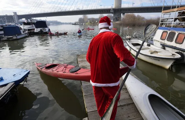 A man wearing Santa Claus costumes prepares his kayak on the Sava river in Belgrade, Serbia, Saturday, December 31, 2022. (Photo by Darko Vojinovic/AP Photo)