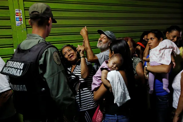 A Venezuelan soldier controls the crowd as people queue trying to buy basic food during a special inspection to a municipal market in Caracas, Venezuela July 15, 2016. (Photo by Carlos Garcia Rawlins/Reuters)