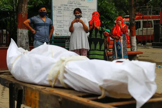 Relatives mourn as they stand next to the body of a man who died due to the coronavirus disease (COVID-19), at a crematorium, in New Delhi, India September 7, 2020. (Photo by Adnan Abidi/Reuters)
