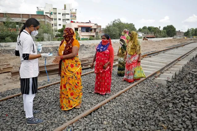 A healthcare worker puts a pulse oximeter on a woman's finger to check her oxygen level during survey for the coronavirus disease (COVID-19) at the construction site of a railway track, amidst the spread of the disease in Babla village on the outskirts of Ahmedabad, India, September 15, 2020. (Photo by Amit Dave/Reuters)