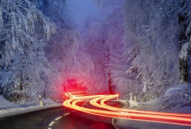 Long time exposure photo shows cars driving through a forest of the Taunus region near Frankfurt, Germany, Thursday, January 26, 2023. (Photo by Michael Probst/AP Photo)
