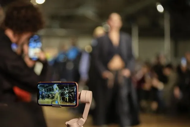 A guest records on a cell phone as models wear creations as part of the Tokyo James women's Fall-Winter 2023-24 collection presented in Milan, Italy, Saturday, February 25, 2023. (Photo by Antonio Calanni/AP Photo)