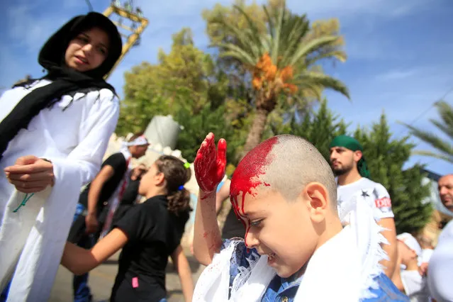 A Shi'ite Muslim boy bleeds after tapping his forehead with a razor during a religious procession to mark Ashura in Nabatiyeh town, southern Lebanon October 12, 2016. (Photo by Ali Hashisho/Reuters)
