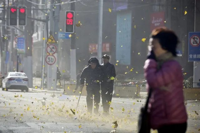 People walk along a street on a windy day in central Shanghai, December 16, 2014. (Photo by Aly Song/Reuters)