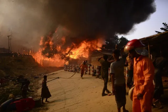 Rohingya refugees try to douse a major fire in their Balukhali camp at Ukhiya in Cox's Bazar district, Bangladesh, Sunday, March 5, 2023. A massive fire raced through a crammed camp of Rohingya refugees in southern Bangladesh on Sunday, leaving thousands homeless, a fire official and the United Nations said. (Photo by Mahmud Hossain Opu/AP Photo)