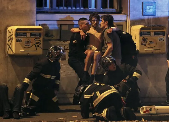 French fire brigade members aid an injured individual near the Bataclan concert hall following fatal shootings in Paris, France, November 13, 2015. (Photo by Christian Hartmann/Reuters)