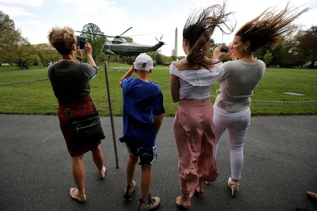 Visitors fight with the wind as the Marine One helicopter with U.S. President Donald Trump departs from the White House in Washington, U.S., April 28, 2018. (Photo by Yuri Gripas/Reuters)