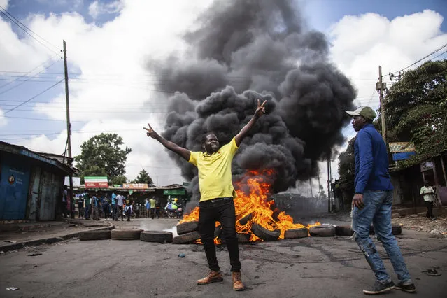 Protesters react next to a burning barricade during a mass rally called by the opposition leader Raila Odinga over the high cost of living, in Kibera Slum, Nairobi, Kenya, Thursday, March 30, 2023. Police in Kenya are on high alert ahead of the third round of anti-government protests organized by the opposition that has been termed as illegal by the government. Police chief Japheth Koome insists that Thursday protests are illegal but the opposition leader Raila Odinga says Kenyans have a right to demonstrate. (Photo by Samson Otieno/AP Photo)