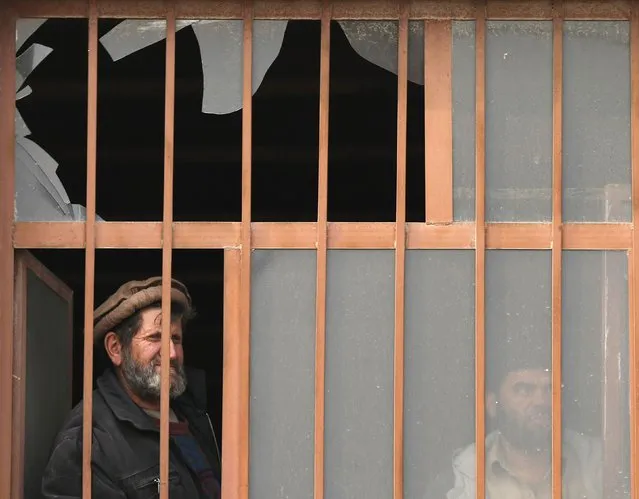 Afghan men look out from the broken window of a shop after a suicide attack in Kabul January 5, 2015. (Photo by Mohammad Ismail/Reuters)