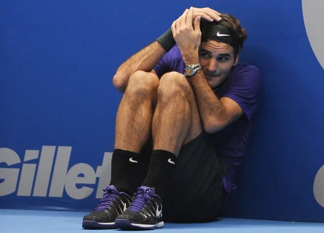 Swiss tennis player Roger Federer jokes to hide from a serve of French Jo-Wilfried Tsonga as he asks a ballboy to play for him during an exhibition match held at the Ibirapuera Gymnasium in Sao Paulo, Brazil, on December 8, 2012. (Photo by Yasuyoshi Chiba/AFP Photo)
