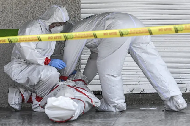 Police officers wearing protective suits remove the corpse of a man who died in the street  in Medellin, Colombia, on May 6, 2020 amid the Covid-19 coronavirus pandemic. More than 15,000 people have been killed by the novel coronavirus in Latin America and the Caribbean as of 0230 GMT Wednesday, according to an AFP tally based on official reports. (Photo by Joaquin Sarmiento/AFP Photo)