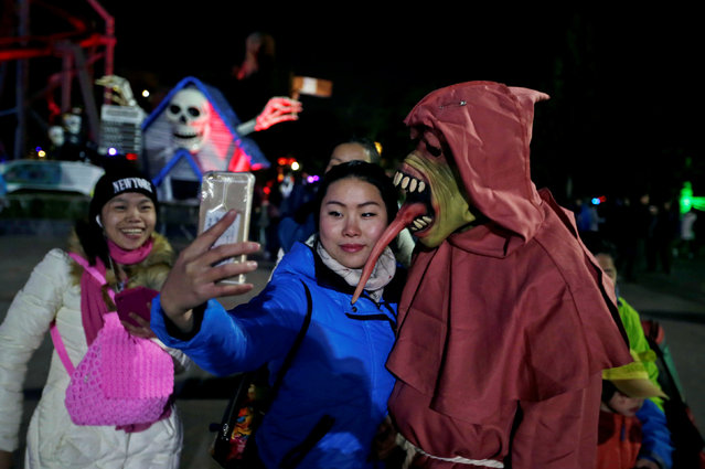 A woman takes a selfie with a performer during a Halloween parade at Happy Valley park in Beijing, China October 31, 2016. (Photo by Jason Lee/Reuters)