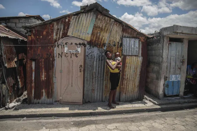 A woman poses for a photo outside her makeshift home built after gangs set her home on fire, in the Cite Soleil slum of Port-au-Prince, Haiti, Thursday, April 20, 2023. (Photo by Joseph Odelyn/AP Photo)