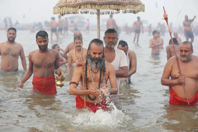 Indian Hindu holy men take holy dips at Sangam, the confluence of the rivers Ganges and the Yamuna on “Mauni Amavasya” or new moon day, an auspicious bathing day during the annual month long Hindu religious fair “Magh Mela” In Prayagraj, India. Thursday, February 11, 2021. Hundreds of thousands of Hindu pilgrims take dips in the confluence, hoping to wash away sins during the month-long festival. (Photo by Rajesh Kumar Singh/AP Photo)