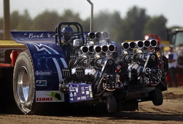 A driver competes in his tractor during the Tractor Pulling Euro Championships in the western German town of Fuechtorf September 9, 2012. Eighty teams from across Europe participated in the two-day competition where high-powered tractor prototypes must pull a trailer down a 100-metre (328 ft) track as far as possible. (Photo by Ina Fassbender/Reuters)