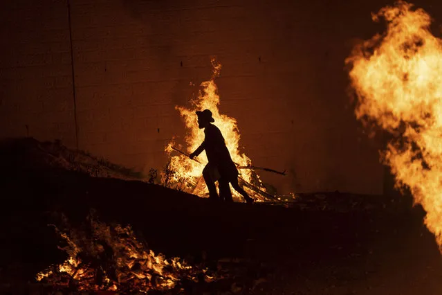 An ultra-Orthodox Jewish man walks through bonfires during Lag BaOmer celebrations in Jerusalem, Tuesday, May 9, 2023. Lag BaOmer celebrations commemorate the end of a plague said to have decimated Jews in Roman times. (Photo by Ohad Zwigenberg/AP Photo)