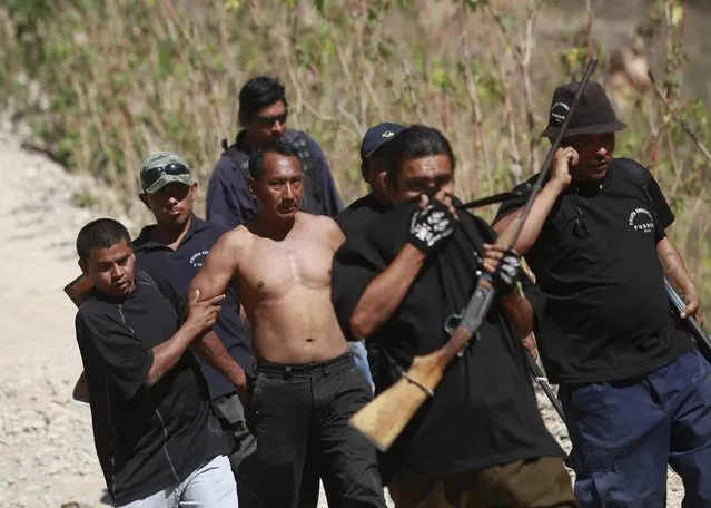 Members of the Community Police of the FUSDEG (United Front for the Security and Development of the State of Guerrero) walk with a man that they captured after a shootout against a group, that villagers suspect are members of a local gang, at a hill in the village of Petaquillas, on the outskirts of Chilpancingo, in the Mexican state of Guerrero, February 1, 2015. (Photo by Jorge Dan Lopez/Reuters)