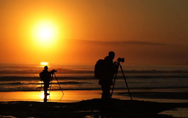 Photographers capture the sun rising over Bamburgh beach in Northumberland, UK on August 29, 2016. Britons had barbecue weather on bank holiday Monday as the warm spell continues. (Photo by Owen Humphreys/PA Wire)