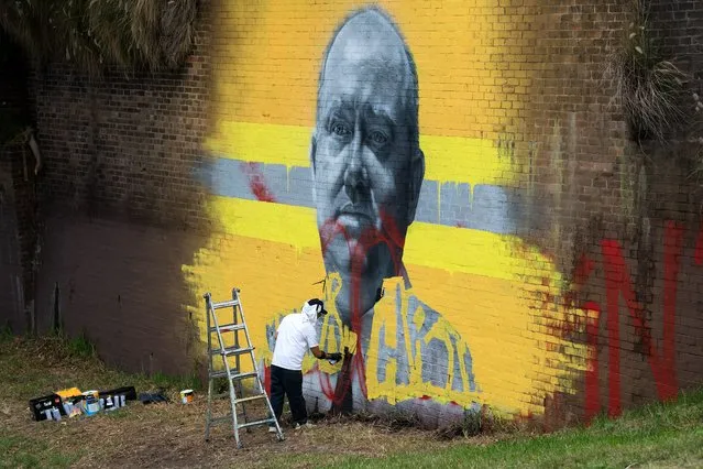 Sydney street artist Sid Tapia repaints his mural of former RFS Commissioner Shane Fitzsimmons after it was defaced in Erskineville, Sydney, Tuesday, February 9, 2021. Police are appealing for public assistance after the newly commissioned mural in Sydney’s inner-west was defaced last night. (Photo by Bianca De Marchi/AAP Image)