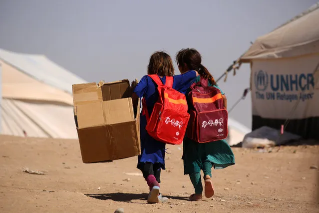 Children walk past UNHCR temporary shelter tents as they head to school on the first day of classes at a refugee camp housing Iraqi displaced families on September 28, 2016 in the Kurdish town of Derik (aka al-Malikiyah in Arabic), in the northeastern Hasakeh governorate, on the border with Turkey and Iraq. (Photo by Delil Souleiman/AFP Photo)