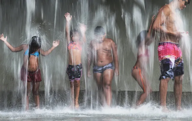 People cool off beneath a water fountain in Madureira Park on December 30, 2015 in Rio de Janeiro, Brazil. A temperature of 104 degrees Fahrenheit was recorded in the city today. According to the World Meteorological Organization, the global average temperature in 2015 will likely be the hottest year ever recorded. (Photo by Mario Tama/Getty Images)