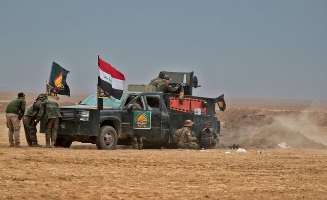 Iraqi Shiite fighters from the Hashed al- Shaabi (Popular Mobilisation) paramilitaries fire at an Islamic State group target as they advance near the village of Tal Abtah, south of Tal Afar, on November 30, 2016, during a broad offencive by Iraq forces to retake the city Mosul from jihadists of the Islamic State group. (Photo by Ahmad Al- Rubaye/AFP Photo)