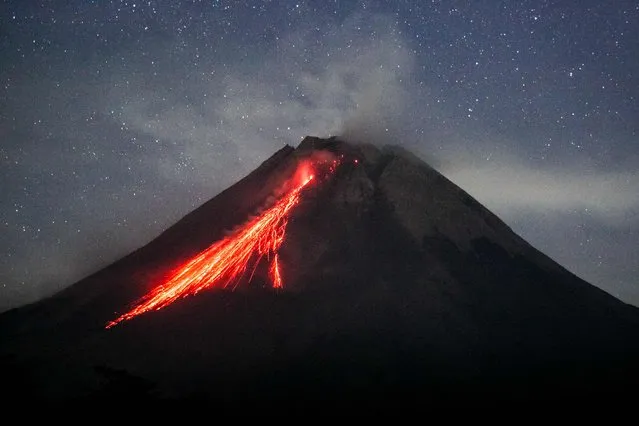 In this picture taken on August 9, 2023, Mount Merapi spews lava onto its slopes during an effusive eruption as seen from Wonokerto village, Yogyakarta. (Photo by Devi Rahman/AFP Photo)