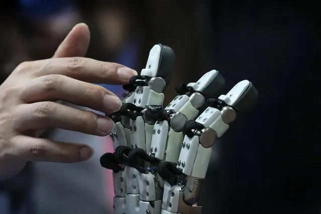 A visitor touches robotic fingers during the annual World Robot Conference at the Etrong International Exhibition and Convention Center on the outskirts of Beijing, Thursday, August 17, 2023. (Photo by Andy Wong/AP Photo)